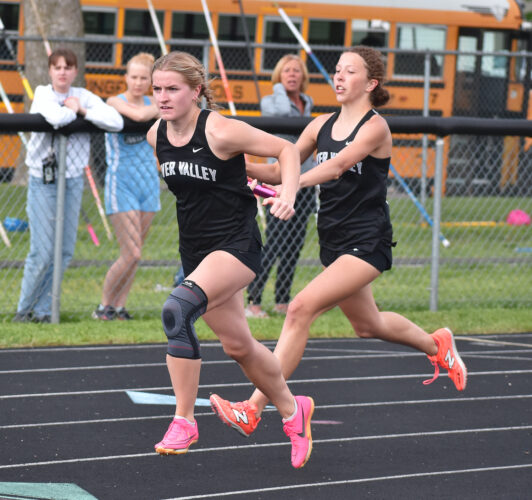 Staff photo by Ari Selvey River Valley’s Hailey Hollar takes the baton from teammate Brynne Ibberson in the girls 4x200-meter relay during the Tomahawk Conference track and field meet Thursday at Sleepy Eye High School.